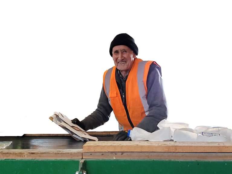 Person smiling works on the recycling line